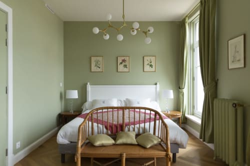 Chambre vert clair à la Gare Godillot BnB à Saint-Ouen, lit blanc, banc en bois, luminaire suspendu moderne et décor botanique