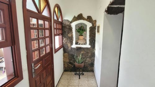 Entrada encantadora de la villa Finca Villanueva en Mala con muros de piedra rústica, puertas de madera y plantas en maceta en nicho arqueado.