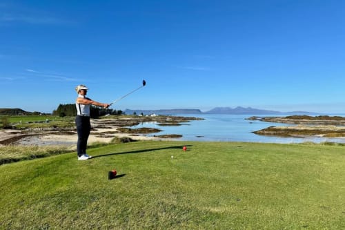 Golfer teeing off at coastal golf course near The Ford Apartment in Perth with mountains and bay views