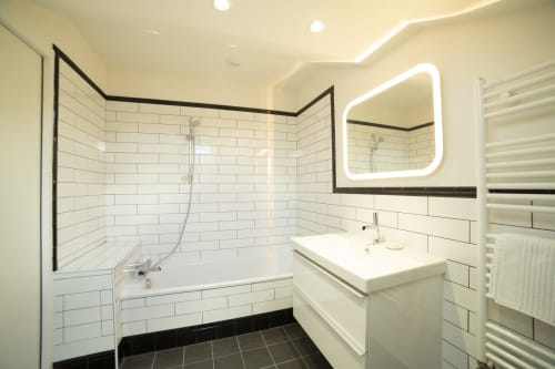 Salle de bains moderne du studio Gare Godillot à Saint-Ouen-sur-Seine avec carreaux métro blancs, miroir LED et douche italienne