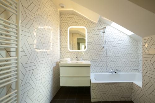 Salle de bain moderne à la Gare Godillot BnB avec carrelage géométrique, miroir éclairé, vasque blanche et baignoire