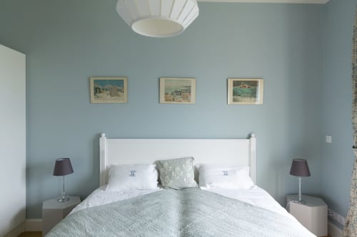 Studio 304 à la Gare Godillot B&B à Saint-Ouen-sur-Seine avec lit blanc, murs bleu clair et affiches de voyage vintage