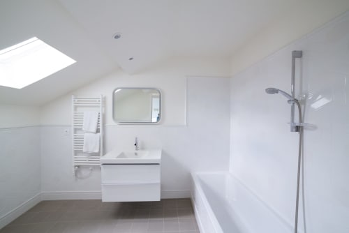 Salle de bain moderne du Gare Godillot BnB à Saint-Ouen-sur-Seine avec lavabo blanc, miroir, porte-serviettes et douche à l'italienne