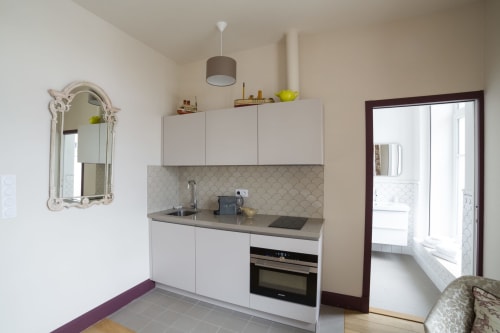 Cuisine studio moderne à la Gare Godillot, Saint-Ouen avec meubles blancs, plan de travail gris et électroménagers en acier inoxydable