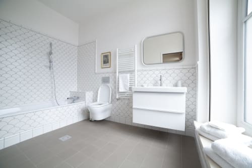 Salle de bains accessible moderne au studio Gare Godillot à Saint-Ouen avec équipements blancs, carrelage coquille et douche plain-pied