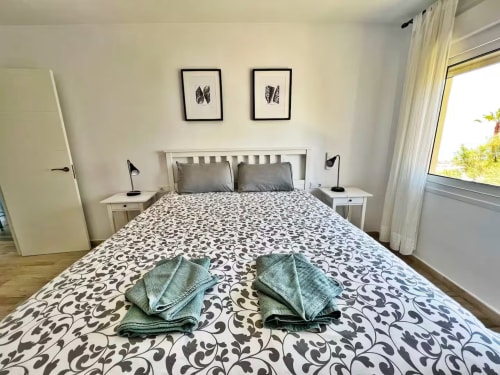 Dormitorio moderno y luminoso en apartamento frente al mar de Fuengirola con ropa de cama estampada, mesillas gemelas y vistas al mar