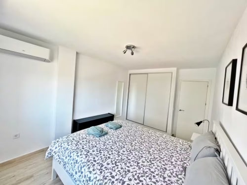 Luminoso dormitorio de apartamento frente al mar en Fuengirola con cama de matrimonio, armarios empotrados y decoración minimalista moderna