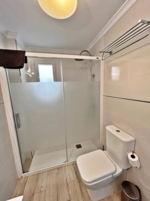 Baño moderno con ducha, inodoro y toallero en apartamento frente al mar en Fuengirola
