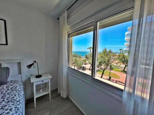 Luminoso apartamento frente al mar en Fuengirola con vistas al mar, ventanales modernos, mobiliario blanco y palmeras