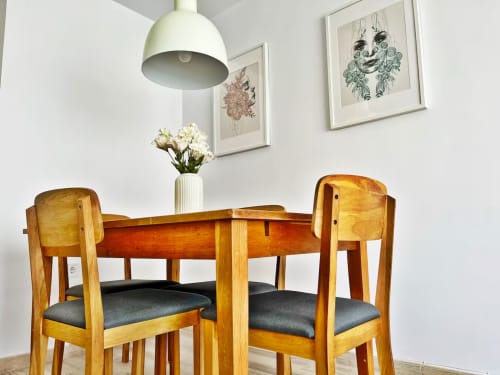 Luminoso comedor en apartamento frente al mar en Fuengirola con mesa de madera, sillas, lámpara colgante y arte botánico en la pared