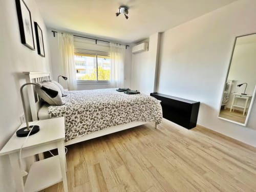 Dormitorio moderno en apartamento frente al mar en Fuengirola con cama doble, suelos de madera y vistas al mar