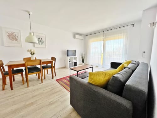 Luminoso apartamento frente al mar en Fuengirola con sofá gris, zona de comedor y mobiliario moderno