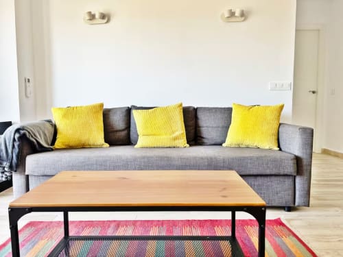 Moderno apartamento frente al mar en Fuengirola con salón luminoso, sofá gris, cojines amarillos y alfombra colorida