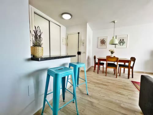 Apartamento moderno y luminoso en Fuengirola con taburetes turquesas, comedor y vistas al mar