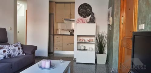 Sala de estar moderna con cocina, mueble blanco de almacenaje y mobiliario oscuro en el Ático del sol de Fuengirola