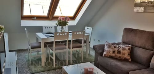 Apartamento luminoso en buhardilla de Fuengirola con tragaluces, comedor, sofá marrón y flores rosas