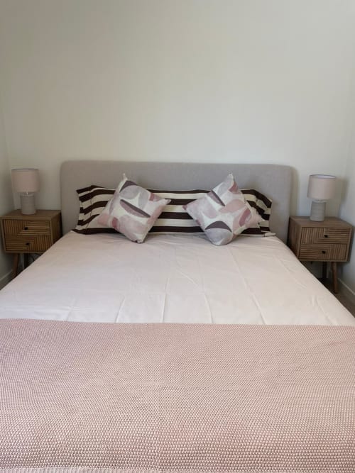 Quarto moderno da Vila Sotto Mayor com cabeceira estofada cinzenta, almofadas às riscas e roupa de cama texturizada rosa em Figueira da Foz