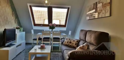 Acogedor salón abuhardillado con sofá marrón, comedor, tragaluces y vistas a la ciudad en Fuengirola