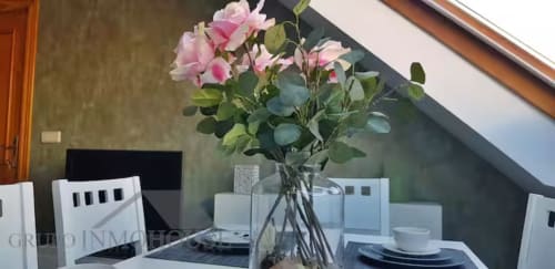 Elegante comedor en apartamento moderno de Grupo Inmo House con flores rosas, mesa servida y claraboya en Fuengirola