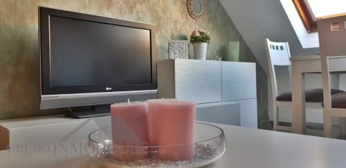 Luminoso salón de apartamento con TV, velas rosas y mobiliario moderno en Grupo Inmo House, Fuengirola