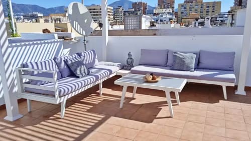 Soleada terraza en la azotea del apartamento Ático del sol en Fuengirola con muebles blancos, cojines rayados y vistas a la montaña