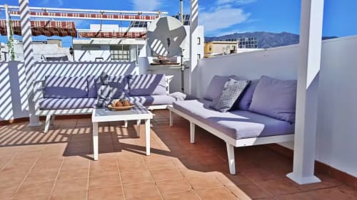 Terraza soleada en la azotea con muebles blancos, cojines morados y vistas a las montañas en apartamento de Fuengirola