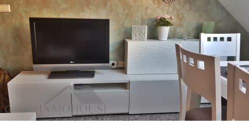 Moderno espacio de trabajo en apartamento de Grupo Inmo House Fuengirola con televisor, mobiliario blanco y zona de comedor