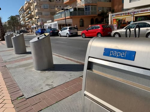 Contenedores subterráneos de reciclaje de papel en la calle Fuengirola con coches aparcados y edificios de apartamentos