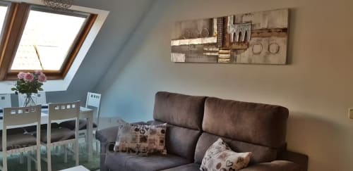 Luminoso apartamento en ático en Fuengirola con sofá marrón, claraboya, comedor y arte moderno en la pared