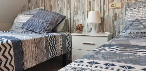 Dormitorio moderno en Grupo Inmo House Fuengirola con camas gemelas, ropa de cama estampada, mesita blanca y lámpara