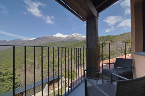 Balcón del Hotel Fonsispa en Renanué con vistas a montañas nevadas, paisaje boscoso y asientos al aire libre.