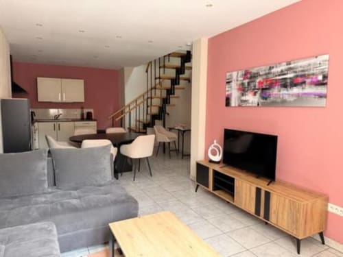 Appartement moderne à l'Hôtel Saint Christophe à Belfort avec murs roses, salon, salle à manger, cuisine, escalier hélicoïdal
