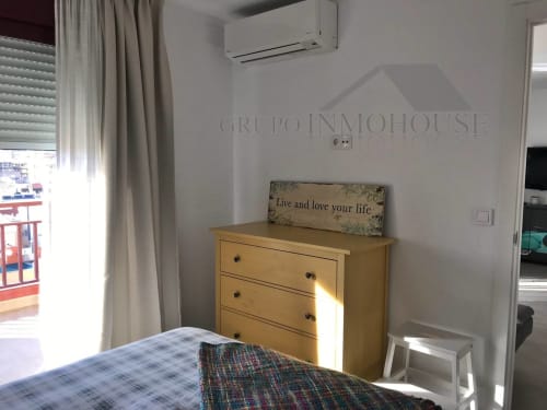 Dormitorio luminoso con tocador de madera, cortinas con vistas al mar y cartel motivacional en Grupo Inmo House, Fuengirola