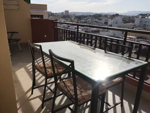 Zona de comedor en balcón con vistas a la ciudad en el apartamento Grupo Inmo House de Fuengirola, con vistas a edificios costeros y montañas