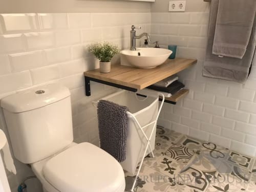 Baño moderno con azulejos blancos tipo metro, vanidor de madera, lavamanos de cerámica y piso decorativo en apartamento frente al mar