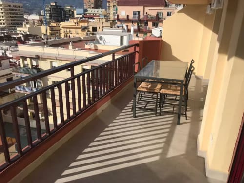 Terraza soleada con vistas a la ciudad en apartamento frente al mar en Fuengirola, con sillas de comedor y barandilla