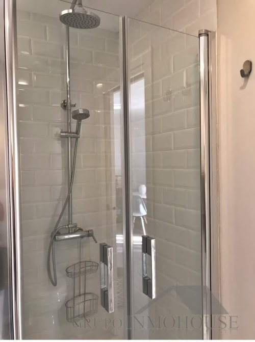 Moderno baño con mamparas de cristal, alcachofa de lluvia y manilla de mano en el apartamento frente al mar de Grupo Inmo House en Fuengirola