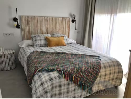 Dormitorio moderno en apartamento frente al mar, Fuengirola. Cama tamaño queen con ropa de cama a cuadros, cabecero de madera y decoración contemporánea.