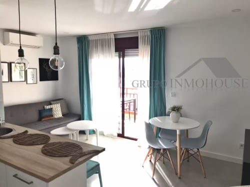 Moderno apartamento frente al mar en Fuengirola con sala abierta, isla de cocina, comedor y cortinas turquesas