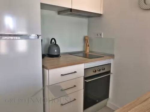 Cocina moderna en apartamento frente al mar en Fuengirola con armarios blancos, encimera de madera y electrodomésticos de acero inoxidable
