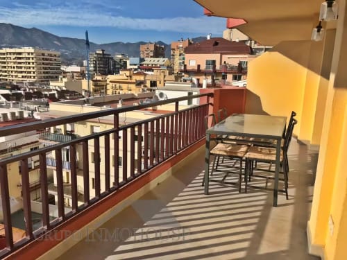 Balcón soleado con vistas a la ciudad de Fuengirola, con mesa, sillas y sombrilla amarilla