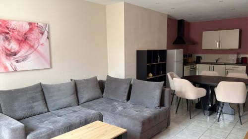 Séjour moderne et ouvert à l'Hôtel Saint Christophe Belfort avec canapé gris, table à manger et cuisine équipée