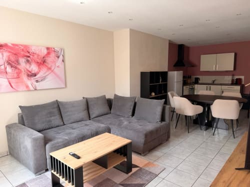 Séjour moderne à l'Hôtel Saint Christophe Belfort avec canapé gris, coin repas et cuisine