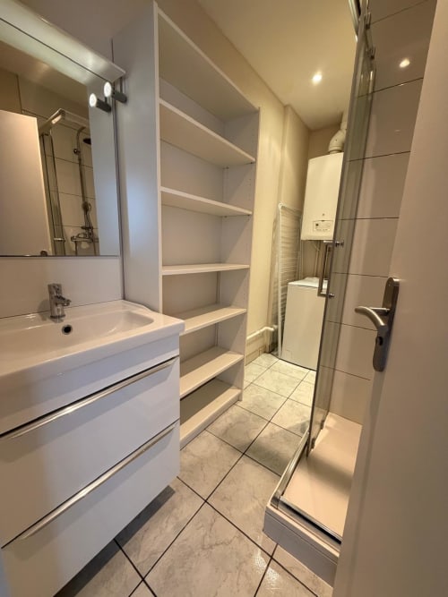 Salle de bain moderne à l'Hôtel Saint Christophe à Belfort avec vasque blanche, grand miroir, rangements, douche et chauffage