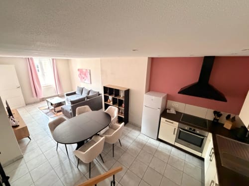 Appartement ouvert à l'Hôtel Saint Christophe Belfort avec coin repas, cuisine, séjour et canapé aux tons crème