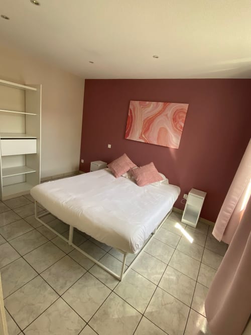Chambre moderne de l'Hôtel Saint Christophe Belfort avec lit blanc, mur d'accent bordeaux et œuvre abstraite rose