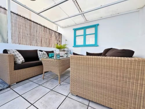 Acogedora zona de descanso en mimbre dentro de acogedor apartamento fuengiroleño con ventana turquesa y vistas a la ciudad