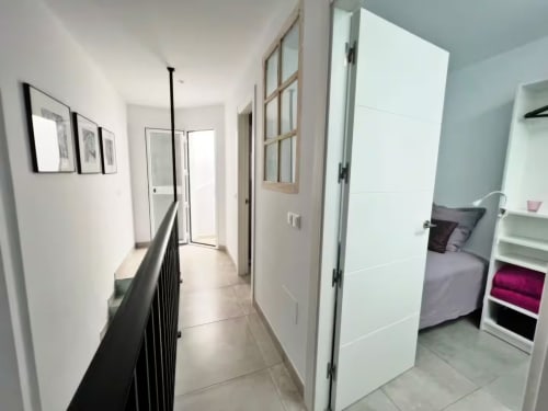 Moderno pasillo en apartamento de Fuengirola con acceso a dormitorio, puertas blancas y diseño contemporáneo