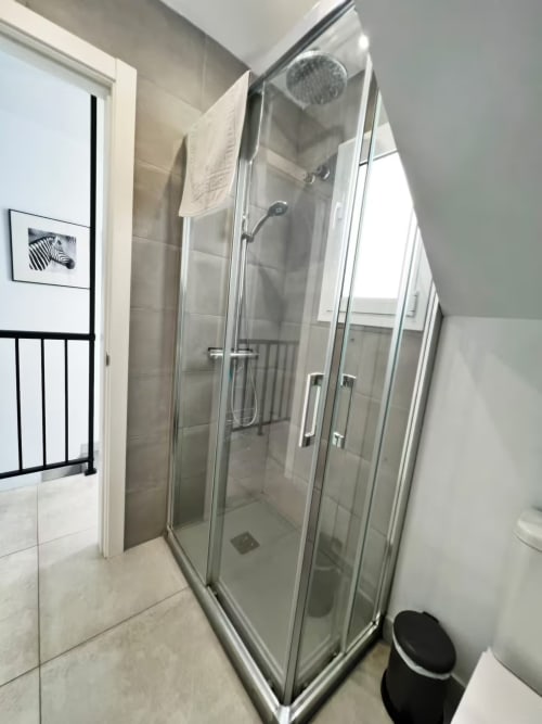 Moderna mampara de ducha en apartamento de Fuengirola con puertas de cristal y alcachofa de lluvia