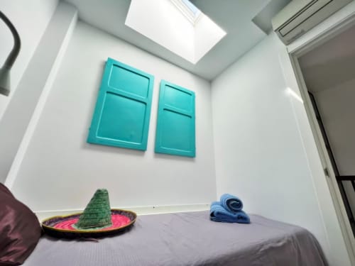 Dormitorio luminoso con arte mural turquesa, cama y sombrero en apartamento Grupo Inmo House, Fuengirola